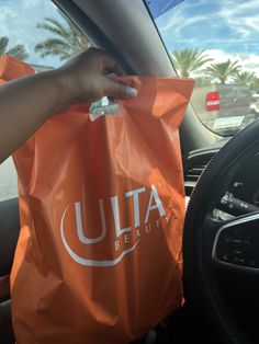 a person holding an orange bag in their hand while sitting in the back seat of a car