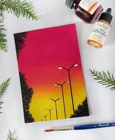 the painting is next to some paintbrushes and a bottle of ink on a white surface