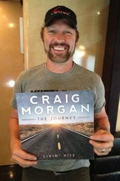 a man holding up a book in front of his face and smiling at the camera