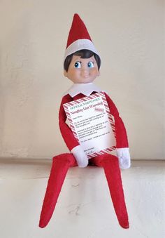 an elf is sitting on top of a shelf holding a paper with the letter to santa claus