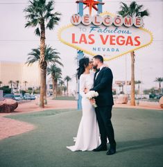 a newly married couple kissing in front of the las vegas sign