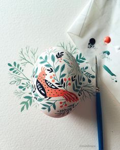 an egg with a bird painted on it next to a pair of scissors and paper