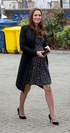 a woman in a black and white dress is walking down the street with her hand on her hip