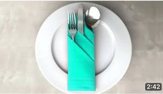 a white plate topped with two silverware and a green napkin on top of it