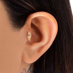 a woman's ear with a small diamond in the shape of a feather on it