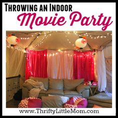 an indoor movie party with red curtains and white drapes on the ceiling, couches in