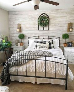 a bedroom with a bed, ceiling fan and window in the corner that has potted plants on it