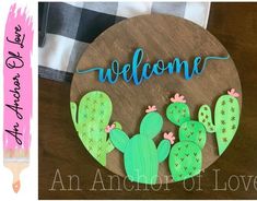 a wooden sign that says welcome with two cactuses