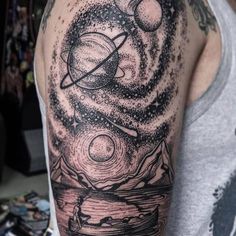 a man with a black and white tattoo on his arm that has planets in the sky