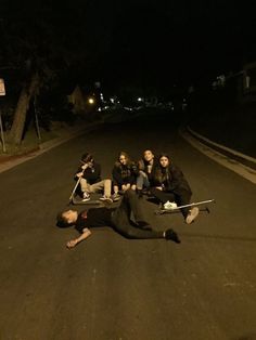 a group of people sitting on the side of a road with skateboards in their hands