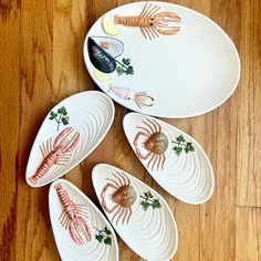 four plates with lobsters painted on them sitting on a wooden floor next to each other