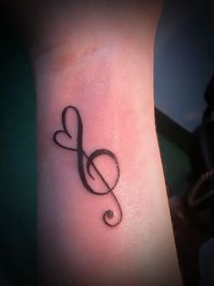 a small tattoo with a treble on it's left arm and the word love written in cursive font