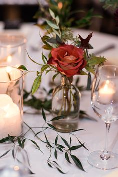 a table with candles and flowers in vases on top of the table is decorated with greenery