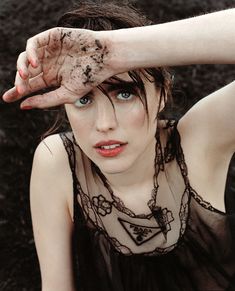 a woman is holding her hand up to her face with mud on it's hands