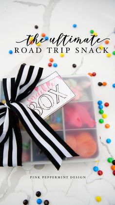 the ultimate road trip snack in a clear box with black and white ribbon on top