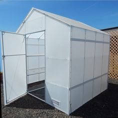 a small white shed sitting on top of a gravel field