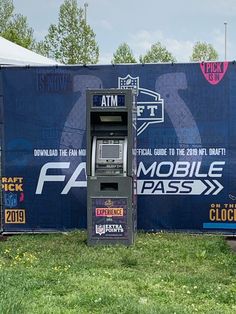 an atm machine sitting in front of a blue wall with the words fa mobile pass on it