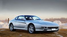 a silver sports car parked in front of snow covered mountains