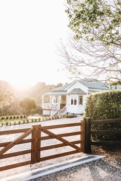 a white house sitting on top of a lush green field next to a wooden fence