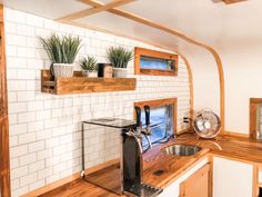 a kitchen with white brick walls and wooden counter tops, an air conditioner on the wall