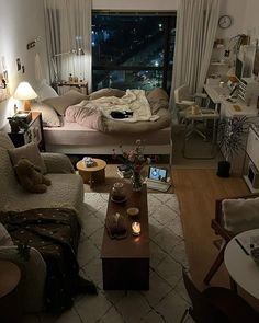 a living room filled with furniture and a large window overlooking the city at night time