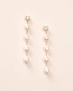 two pairs of pearl and diamond drop earrings on a white background, one is gold