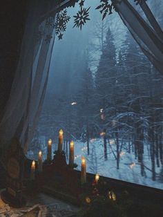 candles are lit in front of a window on a snowy day