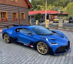 a blue sports car parked in front of a brown brick building on a cobblestone street