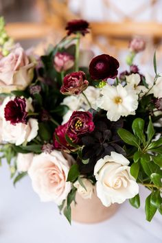 a vase filled with lots of flowers on top of a white cloth covered tablecloth