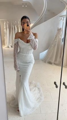 a woman taking a selfie in front of a mirror wearing a white wedding dress