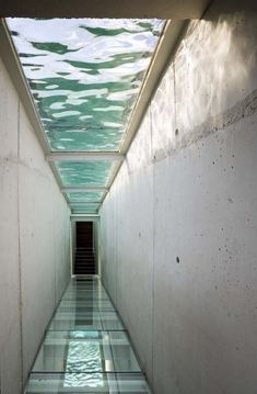 an empty hallway with the light coming in from the ceiling and water on the floor