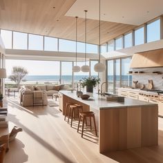 an open kitchen and living room area with large windows overlooking the ocean is pictured in this image