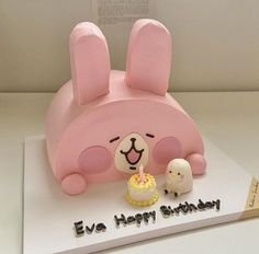 a birthday cake with a pink bunny and sheep figurine on it's side