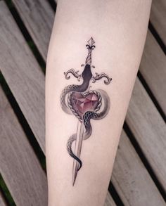 a tattoo on the leg of a woman with a dagger and snake wrapped around it