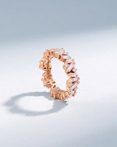 a rose gold ring with three rows of diamonds on the inside and outside, set against a white background