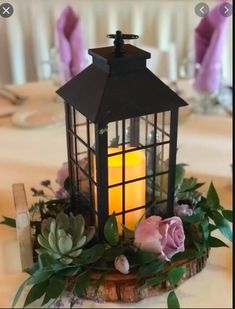 a candle is lit on top of a table with succulents and greenery