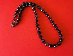 This classic nice quality 18 inch 7mm faceted jet black bead necklace is a classic closet basic. The faceted beads have seed bead spacers and wire strung smaller beads near the clasp to keep the back from being bulky. The necklace is sturdy with a gold tone lobster claw closure. The necklace is a classic inches long. This necklace is a great closet basic in wonderful vintage condition. The beads have a bright carnival sheen. I specialize in finding fun wearable vintage jewelry. Please browse my Classic Faceted Beads Necklace For Gift, Classic Black Beaded Necklaces, Faceted Beaded Necklaces For Party, Black Necklace With Oval Spacer Beads, Party Beaded Necklaces With Faceted Round Beads, Formal Adjustable Beaded Necklace With Faceted Beads, Black Faceted Round Beaded Necklaces, Black Faceted Beaded Necklaces, Black Jewelry With Faceted Oval Beads