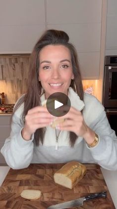 a woman sitting in front of a cutting board with some bread on top of it