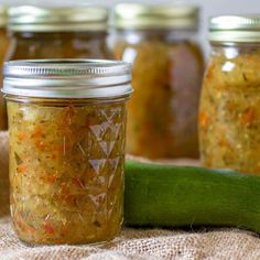 several jars filled with pickles and other condiments next to a cucumber