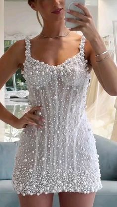 a woman taking a selfie wearing a white beaded dress and holding a cell phone