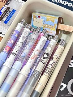 many pens are lined up in a container on the shelf next to some books and other items