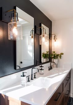 a bathroom with double sinks and two mirrors on the wall above them is lit by three lights