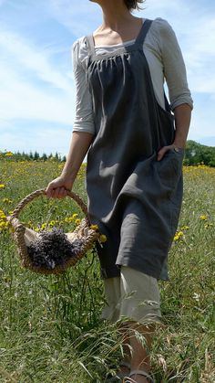 a woman is standing in the grass holding a basket