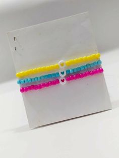 three bracelets with hearts on them are sitting in front of a white card that says i love you