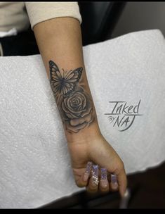 a woman's arm with a butterfly and rose tattoo on the left side of her wrist