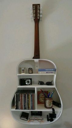 a guitar shaped shelf with books, cds and other items on it's sides