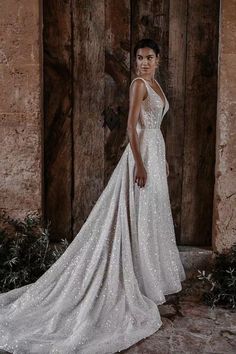 a woman standing in front of a wooden door wearing a wedding dress with sequins