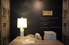 a desk with a lamp and some books on it in front of a chalkboard