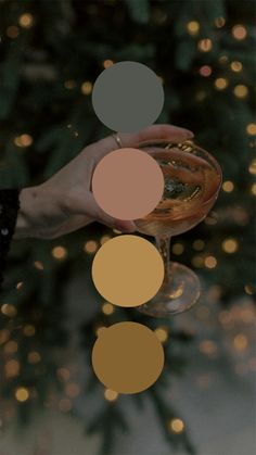 a person holding a wine glass in front of a christmas tree