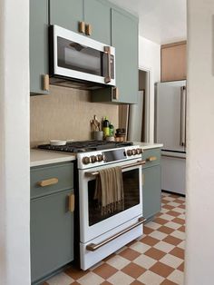 a kitchen with green cabinets and white appliances